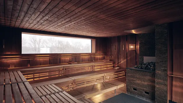 SWG-Sauna-belichtet Auf dem Foto sieht man eine beleuchtet Sauna mit einem Fenster nach draußen. Auf der rechten Seite befindet sich er Saunaofen.