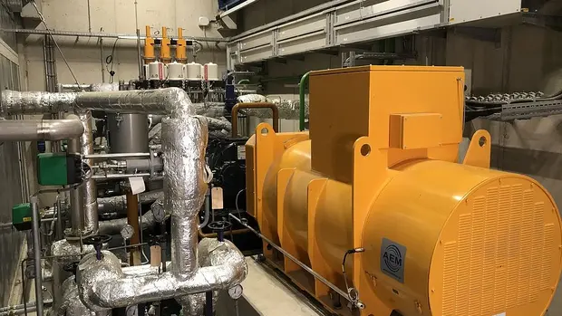 SWG-TREA2-Dampfturbosatz Das Bild zeigt den Innenraum einer industriellen Anlage mit verschiedenen technischen Komponenten. Im Vordergrund befindet sich eine große, gelbe Maschine.A