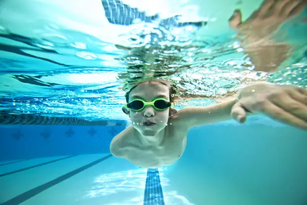 Auf dem Bild ist ein tauchendes Kind mit Taucherbrille in einem Schwimmbecken zu sehen.