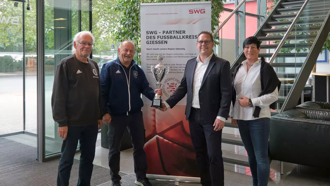 Vier Personen die mit einem Pokal vor einem Rollup des Fußballkreis Gießen posieren