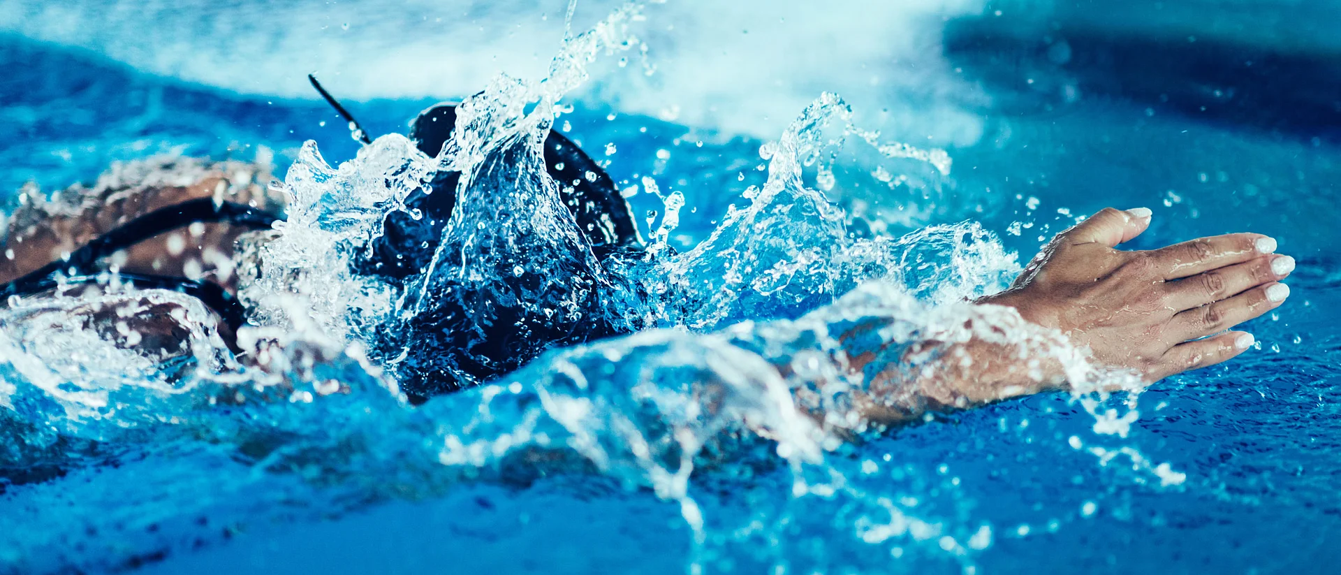 Man sieht einen professioneller Schwimmer in einem Schwimmbecken schwimmen. 