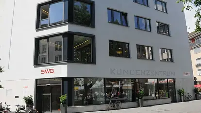 SWG-Kundenzentrum Das Bild zeigt ein modernes, mehrstöckiges Gebäude mit großen Fenstern. An der Fassade ist das Logo "SWG" und die Beschriftung "KUNDENZENTRUM" zu sehen.