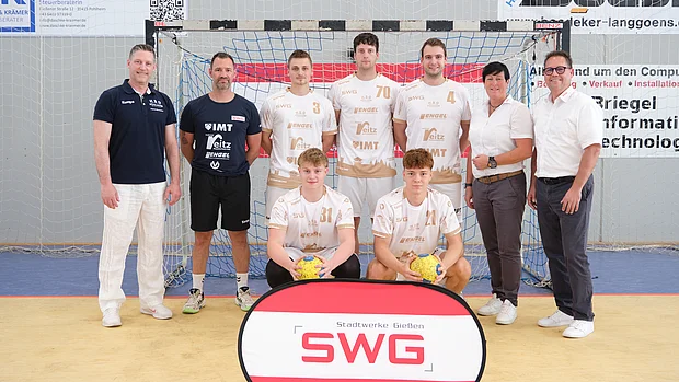 Vereinnsvertreter der HSG Pohlheim sowie Vertreter der SWG posieren vor einem Handballtor