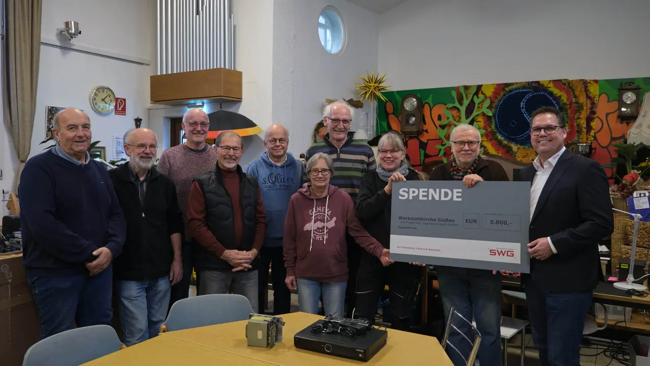 Eine Gruppe von Menschen, die einen Spendencheck überreicht bekommt.