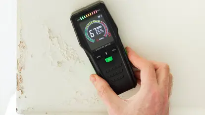 Moisture meter against a wall with rising damp, UK home interior Moisture meter against a wall with rising damp, UK home interior