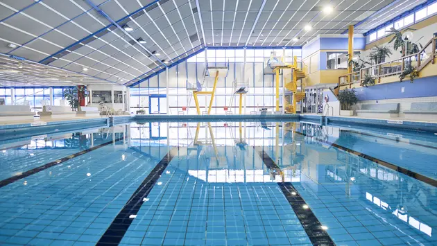 SWG-Sportbecken-mit-Springtürmen Das Bild zeigt ein Sportbecken mit Sprungtürmen und einer Wendeltreppe im Hintergrund.