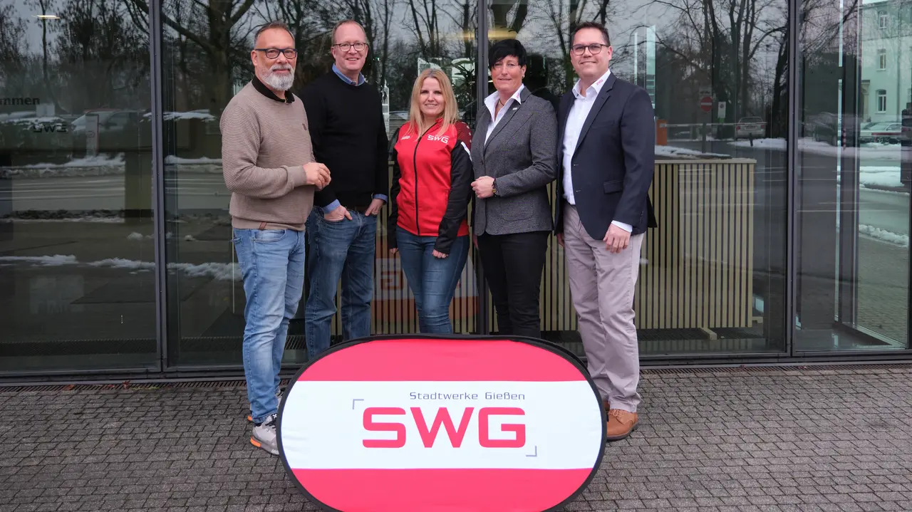 Five people posing together behind a stand with the SWG logo.