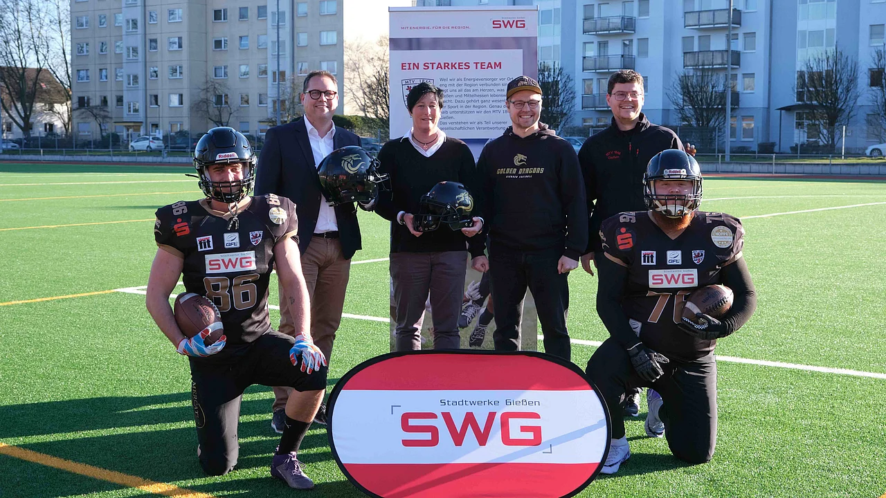 Players and club board members pose on a pitch with representatives of SWG