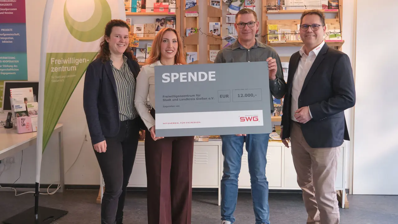 Zwei Frauen links und zwei Männer rechts, die einen Spendenscheck halten.