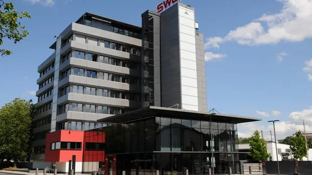 SWG-Lahnstraße-Betriebsgelände Bild von dem SWG-Betriebsgelände in der Lahnstraße. Man sieht ein großes Bürogebäude mit vielen Fenstern sowie das SWG-Logo auf dem Dach des Gebäudes.