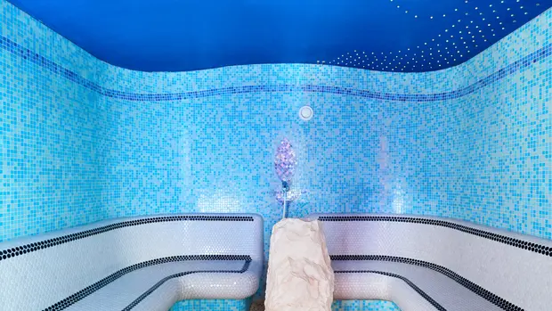 SWG-Spa-Sitzmöglichkeit Auf dem Foto sieht man eine Sitzmöglichkeit in einem Spa-Bereich. Der Raum ist mit blau und Weißtönen gestaltet.