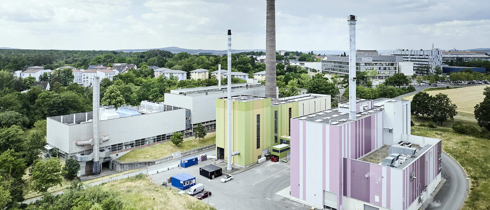 Foto aus der Vogelperspektive von Thermische Reststoffbehandlungs- und Energieverwertungsanlage (Abkürzung: TREA). Man sieht mehrere Fabrikgebäude mit großen Schornsteinen. Um die Fabrik sind Straßen aber auch grüner Wald zu sehen.