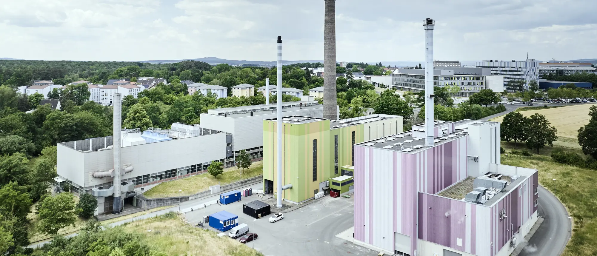Foto aus der Vogelperspektive von Thermische Reststoffbehandlungs- und Energieverwertungsanlage (Abkürzung: TREA). Man sieht mehrere Fabrikgebäude mit großen Schornsteinen. Um die Fabrik sind Straßen aber auch grüner Wald zu sehen.